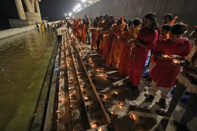 Women lit earthen lamps during a ritual to celebrate of the grand opening of a temple dedicated to Hindu deity Lord Ram at Ayodhya, on the banks of the river Sabarmati, in Ahmedabad, India, Monday, January 22, 2024. (Photo by Ajit Solanki/AP Photo)