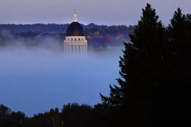 The Maine State House towers over a fog bank rising from the Kennebec River on a chilly morning, Thursday, October 7, 2021, in Augusta, Maine. (Photo by Robert F. Bukaty/AP Photo)