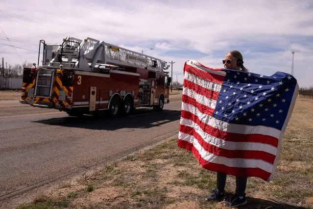 Tammy Latham, a resident affected by the Windy Deuce fire, holds the American flag ahead of the funeral procession for the town fire chief Zeb Smith, who died earlier in the day while responding to a fire, in Fritch, Texas, U.S., March 5, 2024. (Photo by Adrees Latif/Reuters)