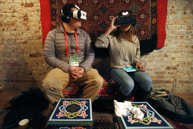 Members of the media try earphones and a headset used for virtual reality at the Sundance Film Festival in Park City, Utah January 23, 2015. The content is viewed on a wraparound-style headset that project a 360-degree panorama, giving viewers the feel of being in the action. (Photo by Jim Urquhart/Reuters)