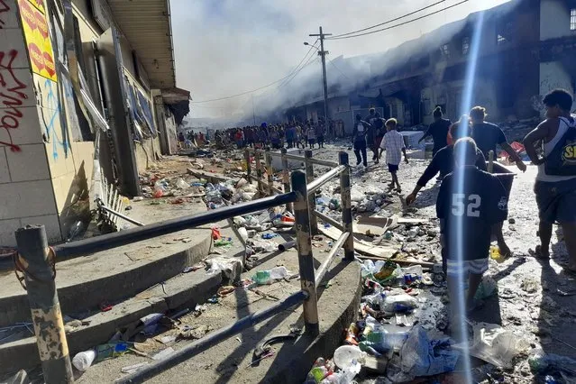 People walk through the looted streets of Chinatown in Honiara, Solomon Islands, Friday, November 26, 2021. Solomon Islands Prime Minister Manasseh Sogavare on Friday blamed foreign interference over his government’s decision to switch alliances from Taiwan to Beijing for anti-government protests, arson and looting that have ravaged the capital Honiara in recent days. (Photo by Piringi Charley/AP Photo)