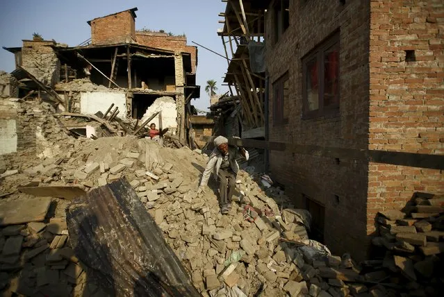 A man carrying a block of wood recovered from his house walks along debris of collapsed houses, a month after the April 25 earthquake in Kathmandu, Nepal May 25, 2015. (Photo by Navesh Chitrakar/Reuters)