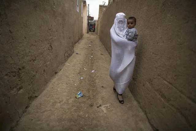 An Afghan woman carries her child as she walks in a narrow alley in Mazar-i-Sharif April 3, 2014. (Photo by Zohra Bensemra/Reuters)