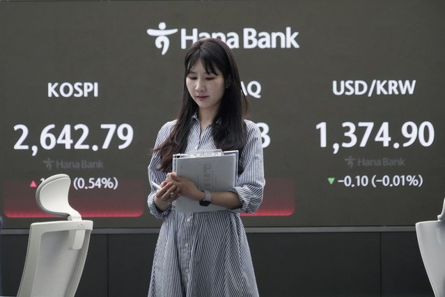 A currency trader passes by the screen showing the Korea Composite Stock Price Index (KOSPI), left, at the foreign exchange dealing room of the KEB Hana Bank headquarters in Seoul, South Korea, Friday, April 26, 2024. Asian shares mostly rose Friday despite worries about the economic outlook and inflation in the U.S. and the rest of the world. (Photo by Ahn Young-joon/AP Photo)