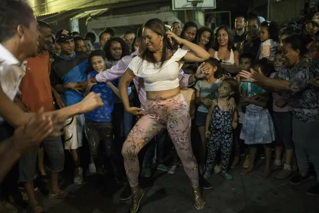 A woman dances with neighbors during a Mother's Day block party in the Petare slum of Caracas, Venezuela, Sunday, May 19, 2019. A decline in armed assaults and killings in Venezuela has a direct link to the economic tailspin that’s helped spark a political battle for control of the once-wealthy oil nation. (Photo by Rodrigo Abd/AP Photo)