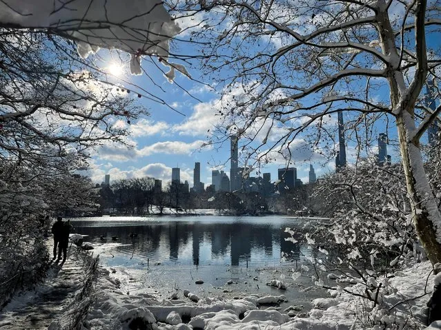 People walk in newly fallen snow in Central Park after a winter storm dropped several inches of snow on the Northeast United States in Manhattan, New York, January 7, 2022. (Photo by Lucy Nicholson/Reuters)