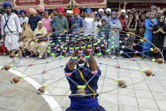 A Sikh devotee demonstrates his “Gatka” traditional martial art skills during the “Nagar Kirtan” procession to mark the 550th birth anniversary of Guru Nanak Dev, the founder of Sikhism, at the Golden Temple in Amritsar on August 2, 2019. (Photo by Narinder Nanu/AFP Photo)