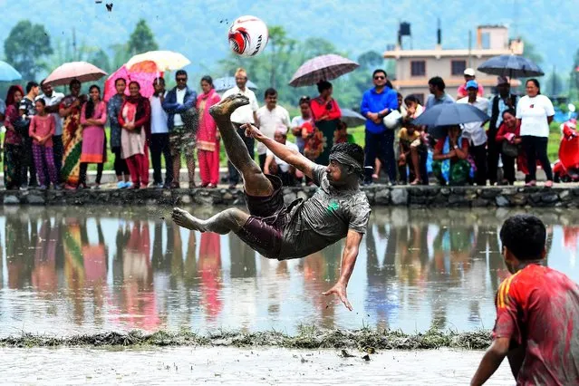 A Nepali youth plays in a rice paddy field during National Paddy Day at Pokhara, some 200 kms west of Kathmandu on June 30, 2019.The farmers are celebrating National Paddy Day on “Asar 15” of the Nepali calendar as the annual rice planting season begins. (Photo by Prakash Mathema/AFP Photo)