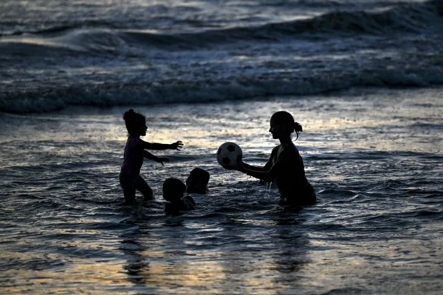 Children play in the Indian Ocean during sunset at a beach in Galle on November 20, 2021. (Photo by Ishara S. Kodikara/AFP Photo)
