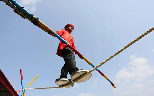 An Indian boy performs a tight rope walk for the entertainment of speactators and to earn livelihood in Bhopal, India, 05 July 2015. (Photo by Sanjeev Gupta/EPA)