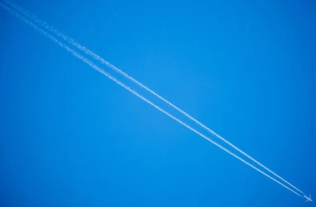 A plane leaves vapor trails in the blue sky as it flies over Frankfurt, Germany, 27 February 2022 (illustration with unidentified plane). Germany, along with other European states, imposed an airspace ban for Russian aircrafts with effect from 27 February 2022 as part of immediate sanctions against Russia following the invasion of Ukraine on 24 February. (Photo by Constantn Zinn/EPA/EFE)