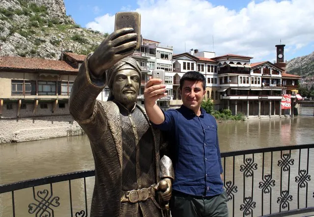 In this May 10, 2015 photo a Turkish man takes a photo of himself with a statue of an Ottoman prince taking a selfie with a cellphone erected in Amasya, Turkey. The statue has met swift and violent criticism and just days after it was erected, vandals – perhaps offended by disparagement of Ottoman history – have hacked off the phone and the prince's sword. (Photo by AP Photo)