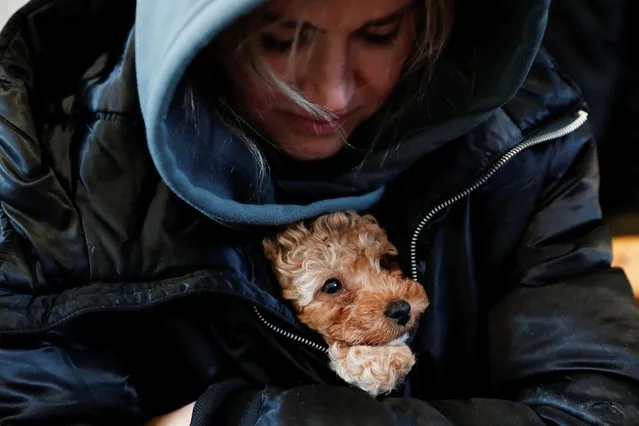 A woman cuddles a dog at the train station after fleeing Russia's invasion of Ukraine, in Zahony, Hungary on March 3, 2022. (Photo by Bernadett Szabo/Reuters)