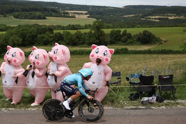 Astana Qazaqstan Team's British rider Mark Cavendish cycles past spectators in inflatable costumes during the 7th stage of the 111th edition of the Tour de France cycling race, 25,3 km individual time trial between Nuits-Saint-Georges and Gevrey-Chambertin, on July 5, 2024. (Photo by Anne-Christine Poujoulat/AFP Photo)