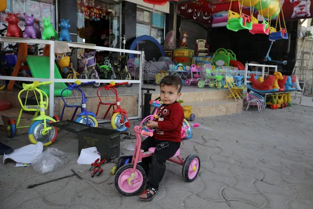 A boy sits on his bicycle in front of a toy store, in eastern Mosul, Iraq April 21, 2017. (Photo by Marko Djurica/Reuters)