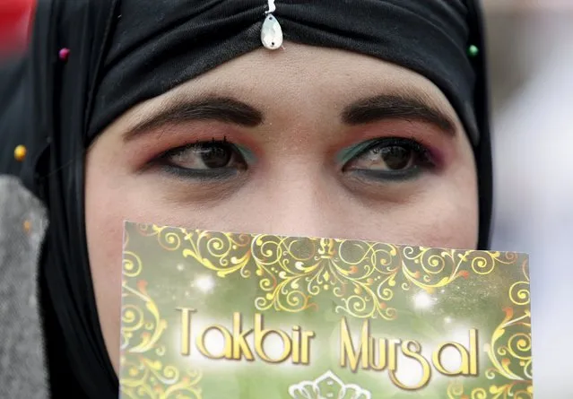 A Filipino Muslim woman holds a copy of religious chants after attending the morning prayers of Eid al-Fitr holiday, marking the end of the holy month of Ramadan, outside the Blue Mosque in Taguig, Metro Manila in the Philippines July 17, 2015. (Photo by Erik De Castro/Reuters)