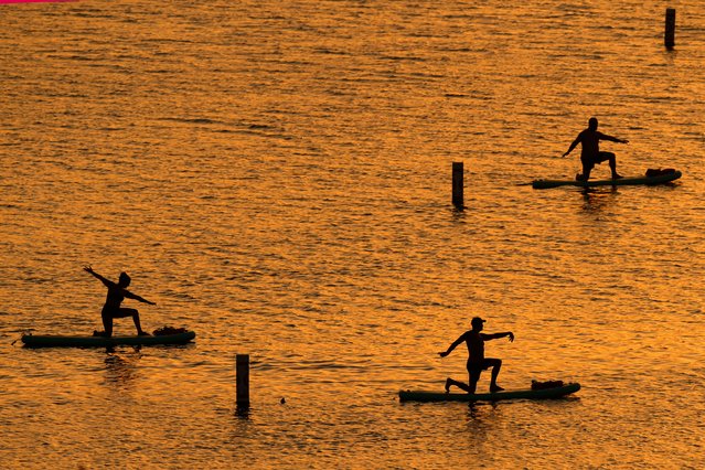 People do yoga poses on paddleboards at sunset as the heat index tops 100 degrees at Olathe Lake, Monday, July 15, 2024, in Olathe, Kan. (Photo by Charlie Riedel/AP Photo)