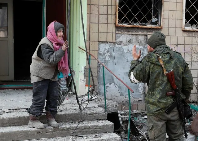 A local resident speaks to a service member of pro-Russian troops outside an apartment building damaged during Ukraine-Russia conflict in the besieged southern port city of Mariupol, Ukraine on March 31, 2022. (Photo by Alexander Ermochenko/Reuters)