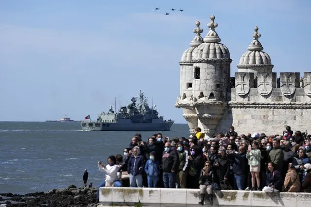 People watch Navy ships, sail boats and military aircraft pass along the Tagus river in Lisbon during celebrations of the 100th anniversary of the first aerial crossing of the South Atlantic, Sunday, April 3, 2022. Portuguese Navy airmen Carlos Gago Coutinho and Artur de Sacadura Cabral flew from Lisbon to Rio de Janeiro in a Fairey III-D seaplane in 1922. (Photo by Armando Franca/AP Photo)