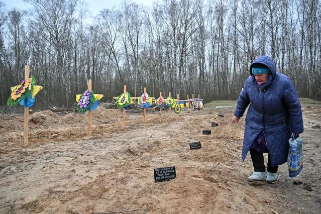 A resident searches for the grave of relatives in a cemetery in Chernigiv, northern Ukraine, on April 5, 2022. Chernigiv, just 50 kilometres from the border with Belarus, was swiftly encircled in the early days of the invasion ordered by Russian President. City officials estimate around 350 civilians have been killed in Chernigiv since the start of the Russain invasion. (Photo by Sergei Supinsky/AFP Photo)