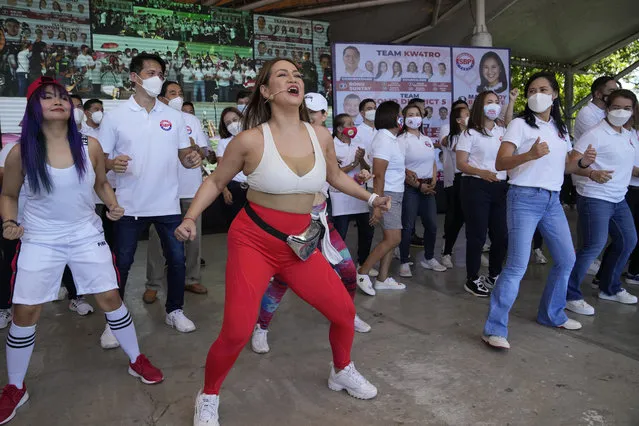 A dancer entertains the crowd beside Quezon City Mayor Joy Belmonte, second from right, as she starts her re-election campaign in Quezon City, Philippines on Friday, March 25, 2022. Candidates for thousands of provincial, town and congressional posts started campaigning across the Philippines Friday under tight police watch due to a history of violent rivalries and to enforce a lingering pandemic ban on handshakes, hugging and tightly packed crowds that are a hallmark of often circus-like campaigns. (Photo by Aaron Favila/AP Photo)
