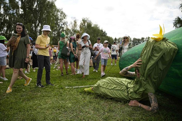 A woman dressed as cucumber lies near an inflatable cucumber during Cucumber Day in the Russian ancient city of Suzdal, some 200 km (124 miles) east of Moscow, Russia, Saturday, July 13, 2024. For almost two decades, Cucumber Day is celebrated in Suzdal in the middle of July, the best time for harvesting the vegetable. The idea to celebrate it came from the employees of the Vladimir-Suzdal Museum-Reserve to reflect historic traditions of vegetable growing in the Suzdal region. (Photo  by Pavel Bednyakov/AP Photo)