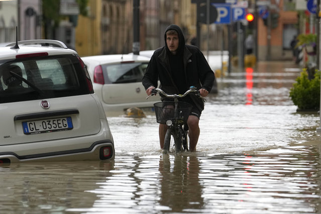 A man pedals in a flooded street in the village of Castel Bolognese, Italy, Wednesday, May 17, 2023. Exceptional rains Wednesday in a drought-struck region of northern Italy swelled rivers over their banks, killing at least eight people, forcing the evacuation of thousands and prompting officials to warn that Italy needs a national plan to combat climate change-induced flooding. (Photo by Luca Bruno/AP Photo)