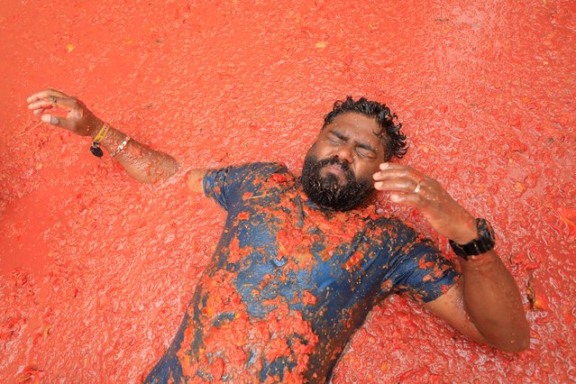 A participant lies in tomato pulp, as people attend the annual food fight festival “La Tomatina” in Bunol, near Valencia, Spain on August 28, 2024. (Photo by Eva Manez/Reuters)