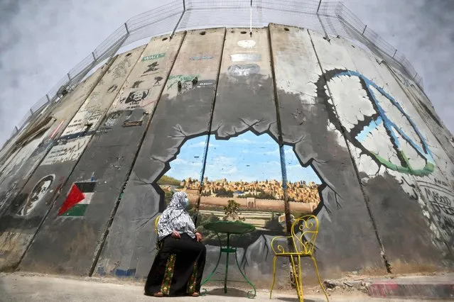 A Palestinian woman looks at a mural depicting Al-Aqsa Mosque compound and Jerusalem's old city on Israel's controversial separation barrier between Jerusalem and the occupied West Bank, in Bethlehem on April 17, 2022. (Photo by Hazem Bader/AFP Photo)