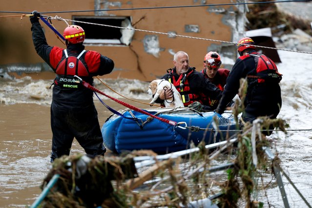 A man holds a dog, aided by rescuers on a flooded street, following heavy rainfall in Jesenik, Czech Republic on September 15, 2024. (Photo by David W. Cerny/Reuters)