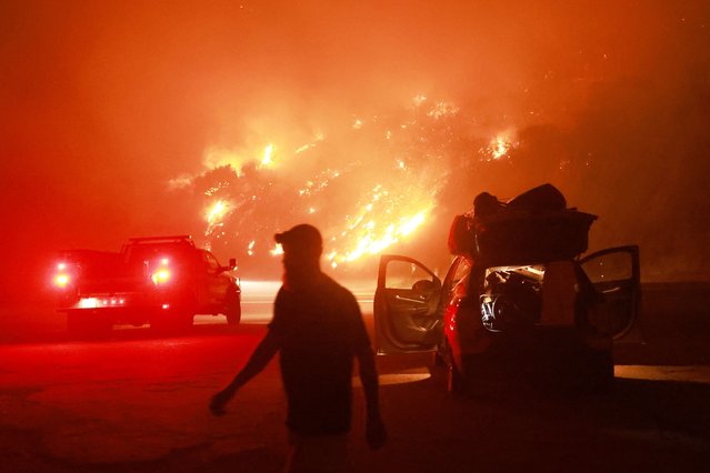 A resident walks by his car packed with belongings as Highway 330 is engulfed by the Line Fire near Running Springs, California, on September 7, 2024. The Line Fire has burned more than 7,000 acres (2,800 hectares). (Photo by David Swanson/AFP Photo)