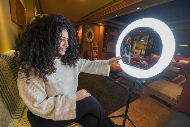 Mariam Ashraf, a teacher and “natural hair influencer”, speaks before a phone on a tripod and lights during a live-stream at her home in Egypt's capital Cairo on March 22, 2022. “Shaggy”, “messy”, “unprofessional”. Natural curls were once looked down upon in Egypt, where Western beauty standards favoured sleek, straight locks. Now, things are changing. (Photo by Khaled Desouki/AFP Photo)