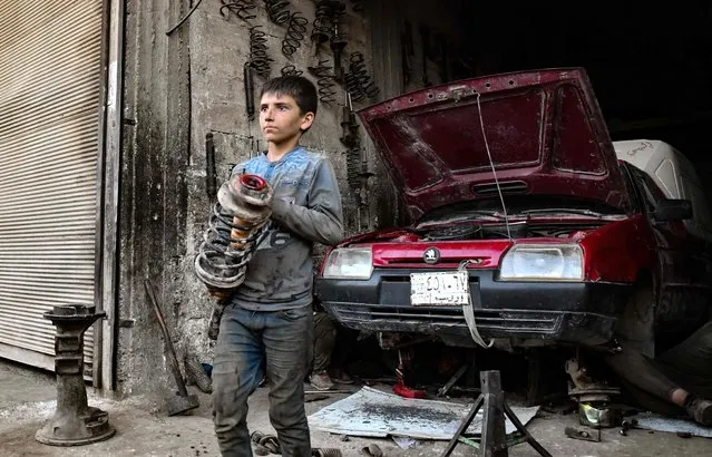 A young Syrian boy works at a car repair shop in the town of Jandaris, in the countryside of the northwestern city of Afrin in the rebel-held part of Aleppo province, on June 11, 2022, a day before the annual World Day Against Child Labour. (Photo by Rami al Sayed/AFP Photo)
