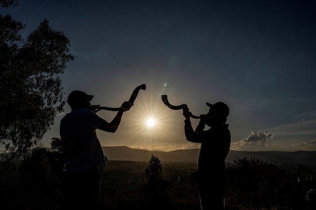 Jewish tourists Patrick Pesach from Switzerland and Alexander Horn from Germany blow shofars, which they say symbolises waking the world up to the reality of the deadly October 7 attack, as the sun sets in the Israeli-occupied Golan Heights on September 23, 2024. (Photo by Ayal Margolin/Reuters)