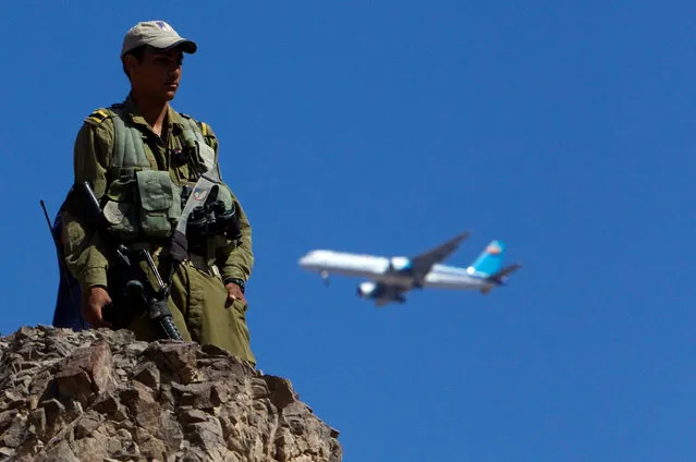 A plane flies overhead as an Israeli soldier stands guard near the Israeli-Egyptian border August 19, 2011. (Photo by Ronen Zvulun/Reuters)