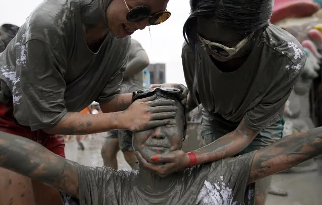 Tourists play in the mud during the Boryeong Mud Festival at Daecheon beach in Boryeong July 18, 2014. About 2 to 3 million domestic and international tourists visit the beach during the annual mud festival, according to the festival organisers. (Photo by Kim Hong-Ji/Reuters)