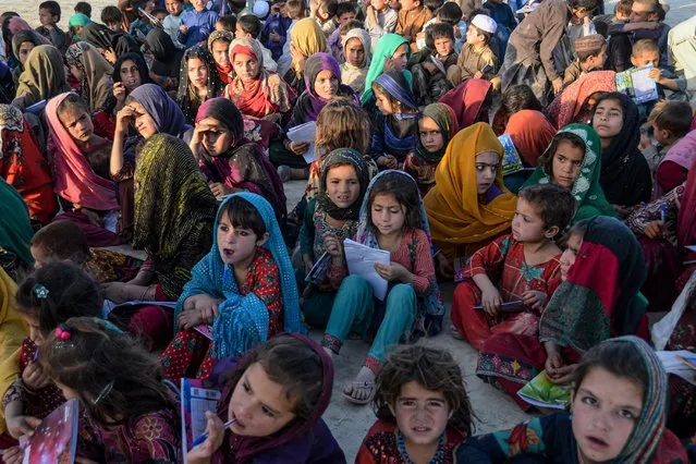Afghan children attend a class on a mobile school in Kandahar on June 5, 2022, which is an initiative by volunteers wherein a vehicle carrying all sort of study material travels from village to village conducting classes for the children. (Photo by Javed Tanveer/AFP Photo)