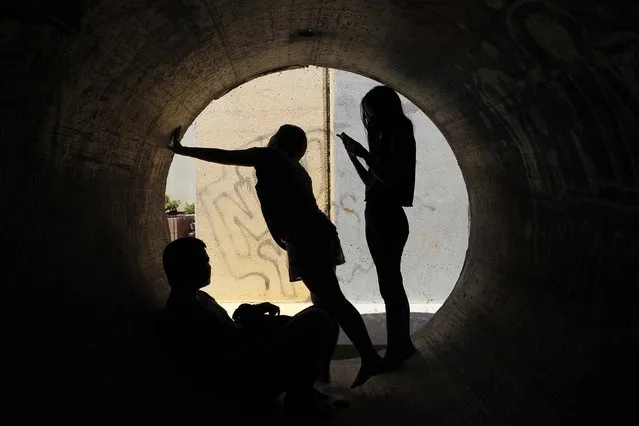 Residents take cover in a concrete pipe used as a bomb shelter, as a siren warning of incoming rockets is sounded in the southern community of Nitzan, near Ashdod July 8, 2014. Israel bombarded dozens of targets in the Gaza Strip on Tuesday, stepping up what it said might become a long-term offensive against Islamist Hamas after a surge in Palestinian rocket attacks on Israeli towns. (Photo by Finbarr O'Reilly/Reuters)