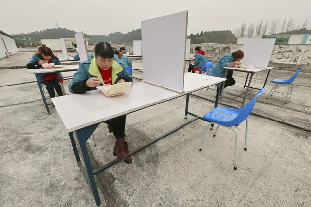In this Friday, February 14, 2020 photo, factory workers are separated by partitions as a precaution against infection as they take their lunch break on the roof of an electronics factory in Suining in southwestern China's Sichuan Province. China reported Saturday a figure of 2,641 new virus cases, a major drop from the higher numbers in recent days since a broader diagnostic method was implemented. (Photo by Chinatopix via AP Photo)