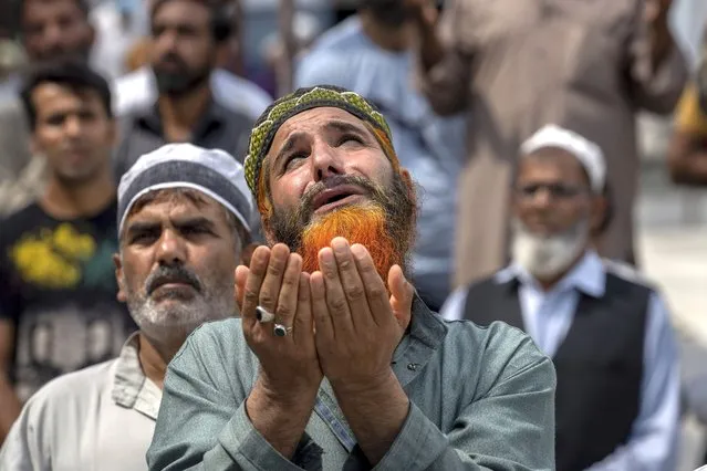 Kashmiri devotees raise their hands and pray as the head priest, displays a relic believed to be a hair from the beard of the Prophet Mohammad during special prayers to observe the Martyr Day of second Khalifa of Islam Hazrat Umar-e- Farooq, at Hazratbal Shrine in Srinagar, Indian controlled Kashmir, Wednesday, July 27, 2022. (Photo by Dar Yasin/AP Photo)