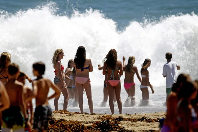 Beachgoers watch large waves crash on the shore at Seal Beach, Calif., Tuesday, August 26, 2014. Residents in Southern California coastal areas filled sandbags and built sand berms Tuesday to ward against possible flooding from big and potentially damaging surf spawned by Hurricane Marie off Mexico's Pacific coast. (Photo by Nick Ut/AP Photo)