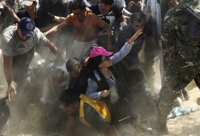 Migrants fall as they rush to cross into Macedonia after Macedonian police allowed a small group of people to pass through a passageway, as they try to regulate the flow of migrants at the Macedonian-Greek border September 2, 2015. (Photo by Ognen Teofilovski/Reuters)