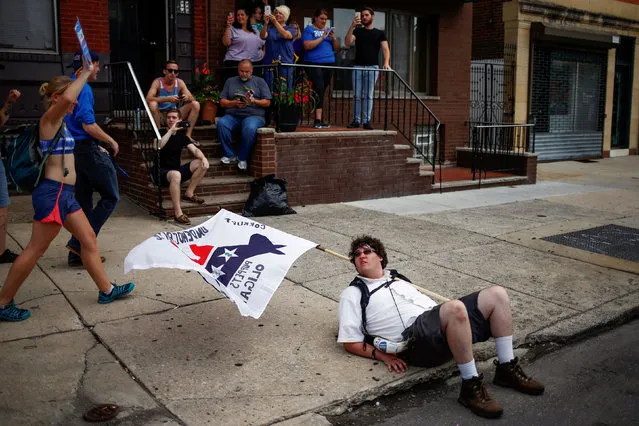 A man takes rest along the sidewalk as demonstrators from various groups, including supporters of U.S. Senator Bernie Sanders, take part in a protest march on the first day of the 2016 Democratic National Convention in Philadelphia, Pennsylvania, U.S. July 25, 2016. (Photo by Adrees Latif/Reuters)