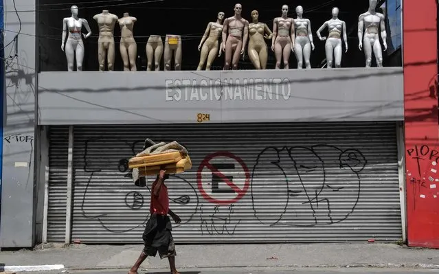 A homeless walks past a closed parking lot and mannequins in downtown Sao Paulo, Brazil, after the city government decreed the closure of shops and stores as a precautionary measure against the spread of the novel coronavirus COVID-19, on March 24, 2020. Latin America's biggest city, the traffic-clogged concrete jungle of Sao Paulo, slowed to an eerily quiet lull Tuesday as it went into partial quarantine in a bid to stop the new coronavirus from ravaging Brazil. (Photo by Nelson Almeida/AFP Photo)