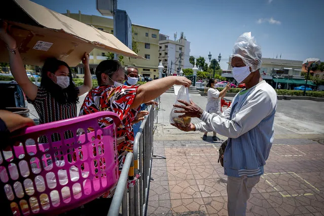 A man wearing a protective mask and a plastic bag over his head receives free lunch near Sanam Luang in Bangkok, Thailand, 20 April 2020. Restaurant owners and other Bangkok residents are providing free meals to those affected by the closure of businesses and shops, a measure imposed to help prevent the spread of the COVID 19 disease caused by the SARS CoV-2 coronavirus. (Photo by Diego Azubel/EPA/EFE/Rex Features/Shutterstock)