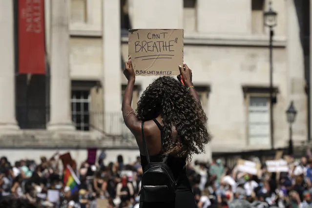A woman holds up a banner as people gather in Trafalgar Square in central London on Sunday, May 31, 2020 to protest against the recent killing of George Floyd by police officers in Minneapolis that has led to protests across the US. (Photo by Matt Dunham/AP Photo)