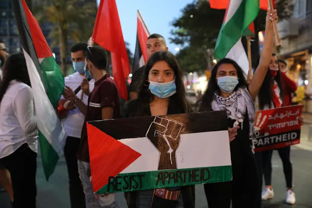 A woman holds up a sign with the Palestinian flag, a Black Power fist and the slogan “Resist Apartheid” as Jewish and Arab Israelis protest against US President Donald Trump's 'peace plan' for the Israeli-Palestinian conflict as they march in Tel Aviv, Israel, 06 June 2020. The Israeli government is reportedly preparing to annex parts of the West Bank that were first occupied by the Israel Defence Force (IDF) in the 1967 Six-Day War. The annexation of up to 30 percent of the occupied Palestinian territory, deemed illegal under extant international law, would fulfill a campaign promise pledged by Israeli Prime Minister Benjamin Netanyahu during the recent general elections. The move has the full backing of the Trump administration – which expressed its support for what it described as “The Deal of the Century” back in January – but is overwhelmingly rejected by most actors in the restive region, including Palestinian leaders and most Arab Israeli citizens. (Photo by Abir Sultan/EPA/EFE)