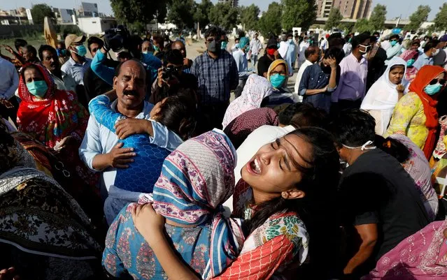 Relatives comfort each other as they mourn the death of Simon Eric, who was killed in a plane crash, during his burial at the Christian's Gora Cemetery in Karachi, Pakistan on May 25, 2020. (Photo by Akhtar Soomro/Reuters)