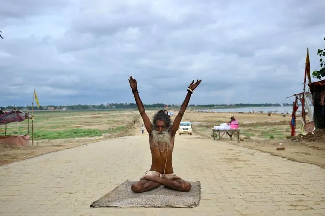 A Sadhu (holy man) performs yoga at the Sangam, the confluence of the rivers Ganges and Yamuna and mythical Saraswati, on the eve of International Yoga Day in Allahabad on June 20, 2020. (Photo by Sanjay Kanojia/AFP Photo)