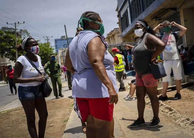 People wearing face masks amid the spread of the new coronavirus wait to enter a government-run food store in Havana, Cuba, Tuesday, May 19, 2020. State media has started a campaign of zero tolerance for anyone attempting to cash in on the fallout from the spread of the new coronavirus, like hoarding and speculative pricing, which has imposed even more distress on Cubans who were already used to shortages and long lines in their efforts to find basic necessities. (Photo by Ramon Espinosa/AP Photo)